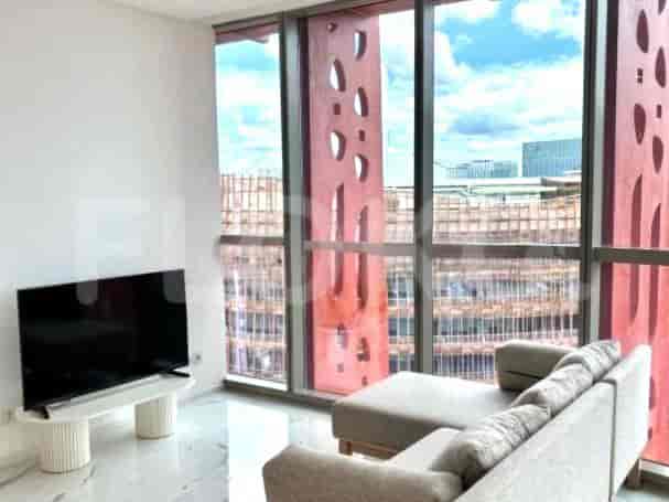A living room with a sectional sofa, a TV, and large windows offering a city view.
