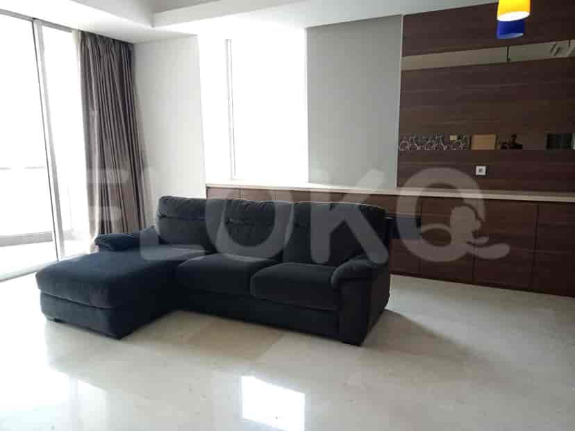 Living room featuring an L-shaped sofa, large windows, and wooden cabinets.