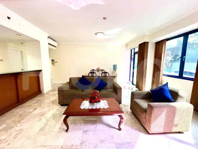 A well-lit living room with a brown sofa and a wooden dining table, showcasing marble flooring and natural light.