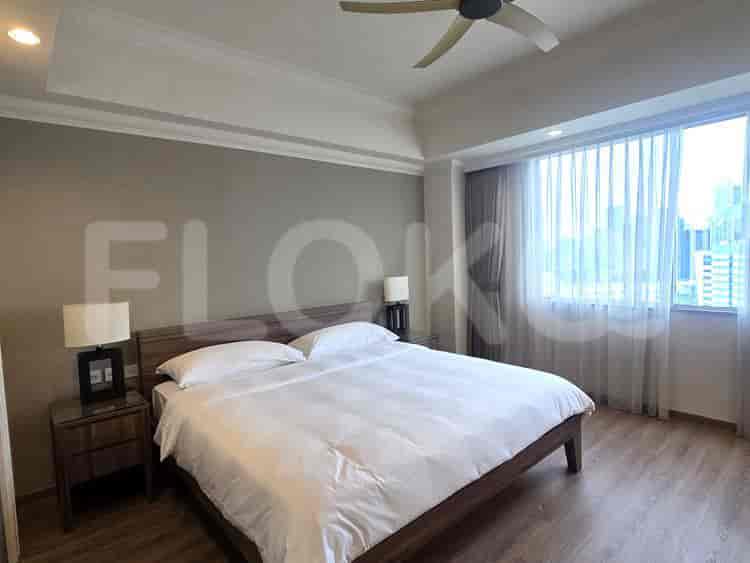A bright bedroom with a king-sized bed, wooden nightstands, and large window with sheer curtains.