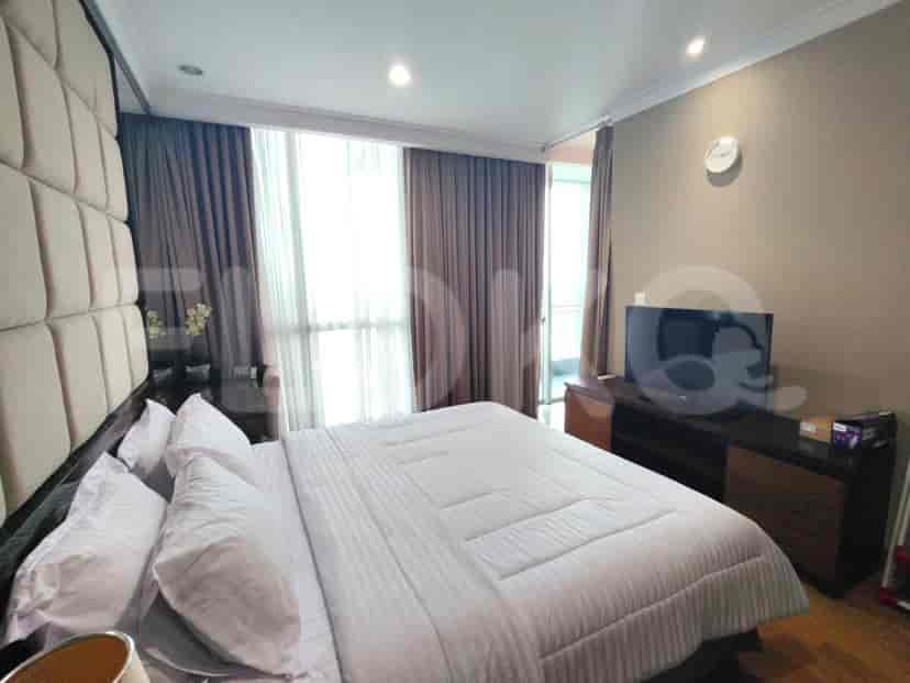A bedroom with a large bed, dark curtains, and a television.