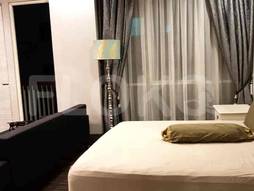 Bedroom with a large bed, sheer curtains, and a floor lamp.