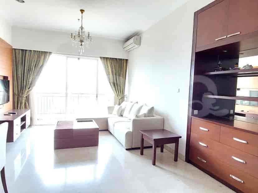 Ruang tamu yang cerah dengan sofa putih, meja kopi kayu, dan lampu gantung kristal.
