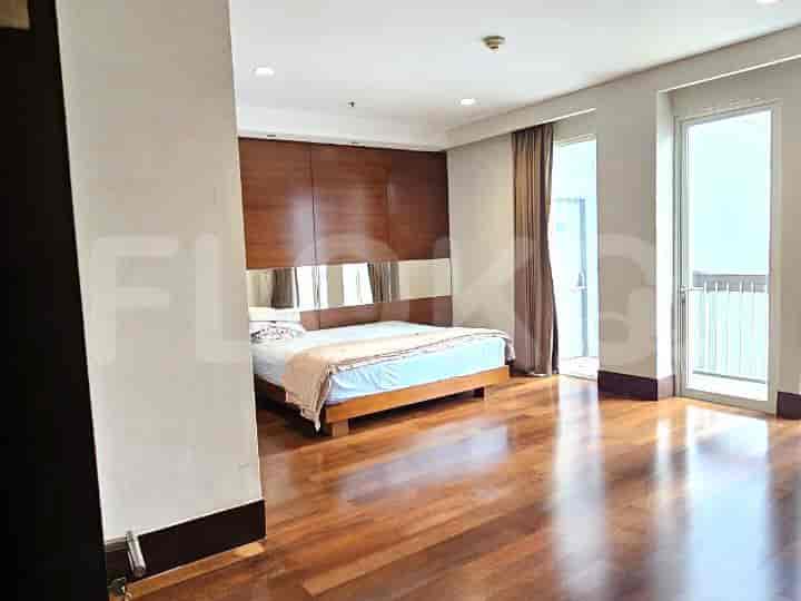 Bedroom with a wooden panel headboard, wooden flooring, and a balcony.