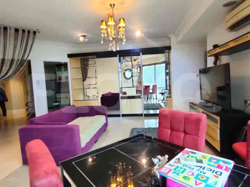 A living room with a purple sofa, dining table and chairs, and a TV.