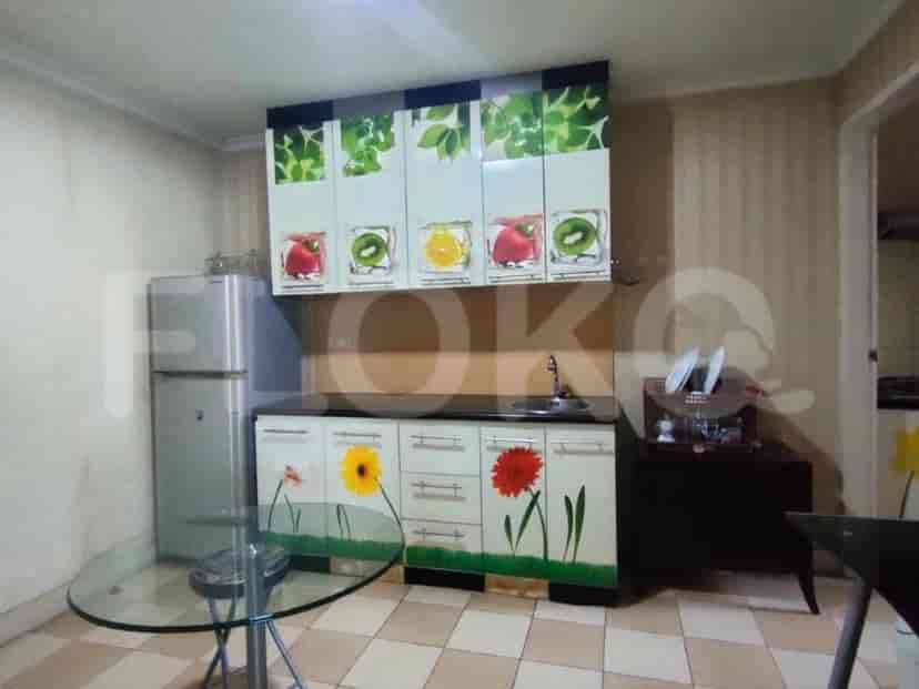 A kitchen with a refrigerator, cabinets, and a table.