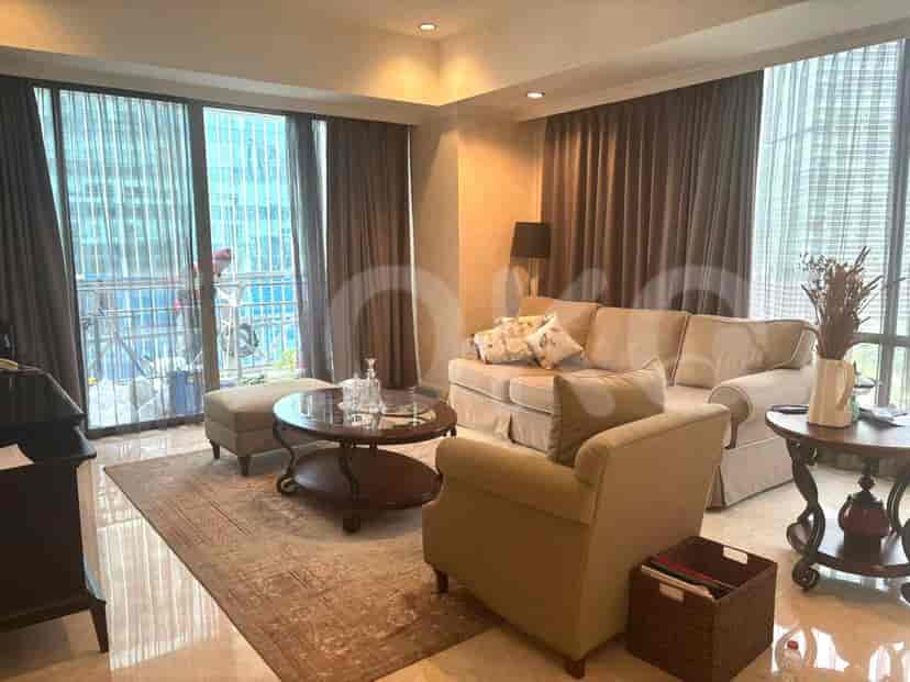 A living room with a sofa, armchair, coffee table, and large windows.