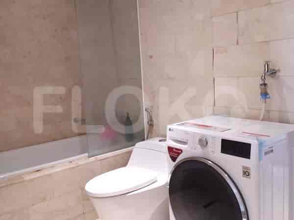 A bathroom with a bathtub, toilet, washing machine, and marble-tiled walls.