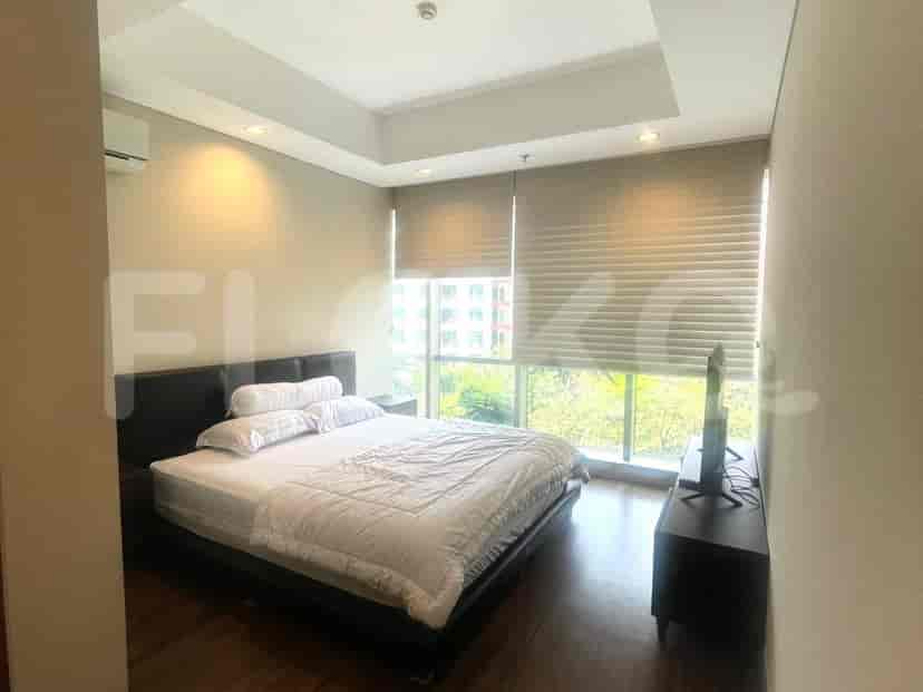 A bedroom with a large bed, TV, and a window with blinds.