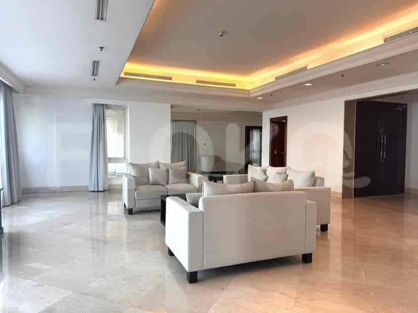A modern living room with white sofas arranged around a coffee table, and a tray ceiling with ambient lighting.