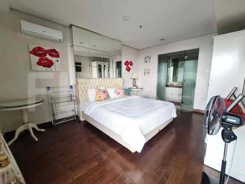 A bedroom with a large bed, mirrored wardrobe, and a small seating area with a glass table.