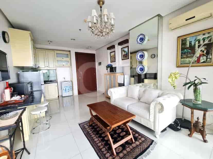 A bright living room with a white tufted sofa, wooden coffee table, and an open kitchen area.