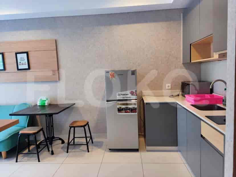 A small kitchen area with gray cabinets, a refrigerator, a microwave, and a sink.