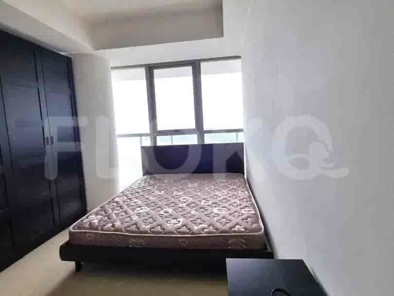 A bedroom with a queen-size bed, a large dark wardrobe, and a window with a view.