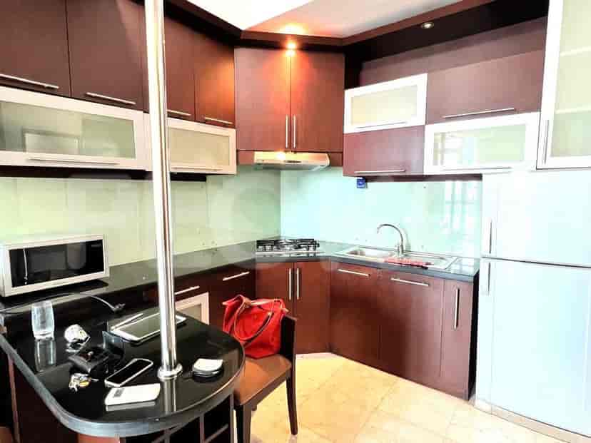Dapur ringkas dengan lemari kayu gelap, meja granit, dan peralatan stainless steel.