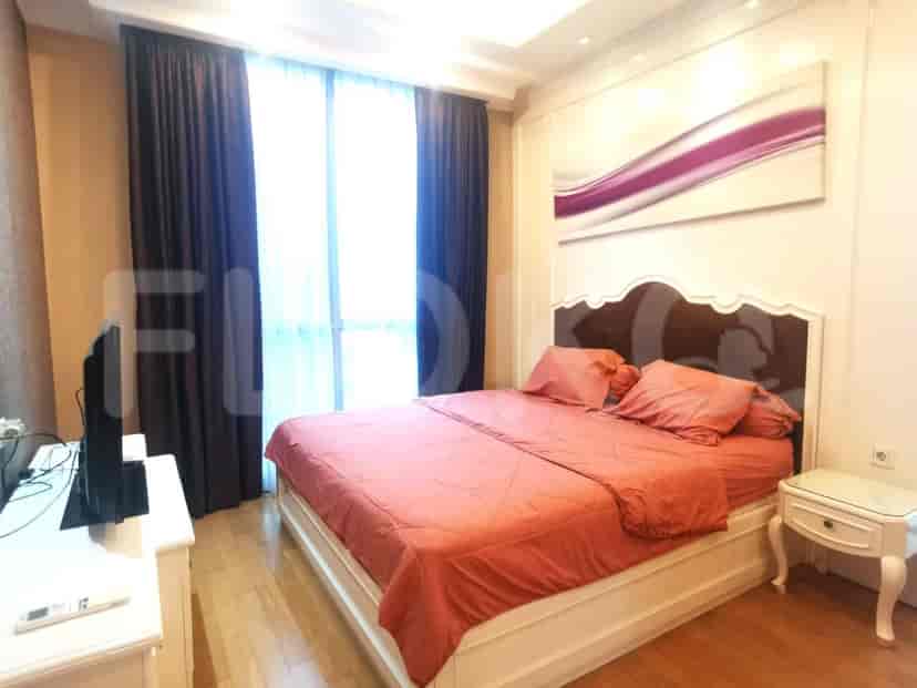 A bedroom with a large bed, dark curtains, and a wall-mounted artwork.