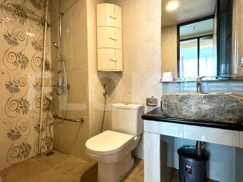 A bathroom with a toilet, a sink with a unique stone basin, and a shower area with decorative tiles.