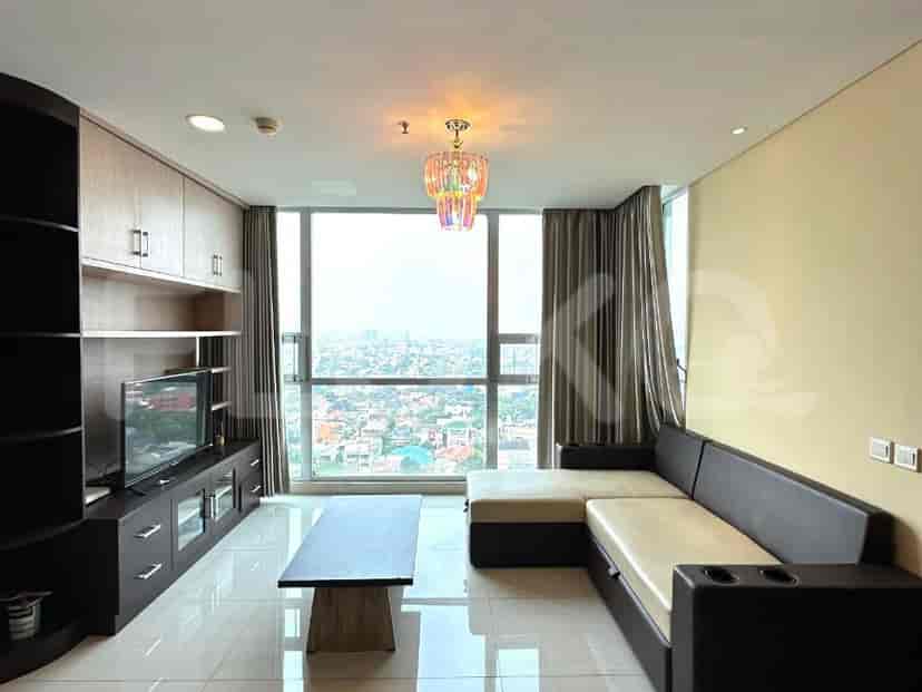A living room with an L-shaped sectional sofa, a TV console with a mounted TV, and a large window offering a city view.