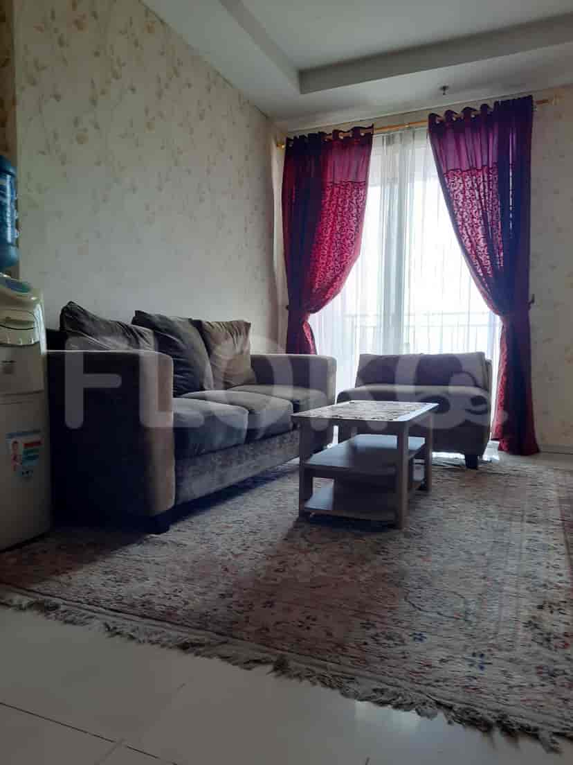 Living room with sofa, rug, and a table near a window with curtains.