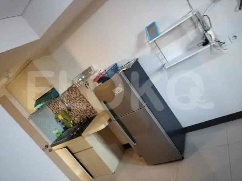 Overview of the apartment showing the kitchen area with refrigerator and the bedroom.