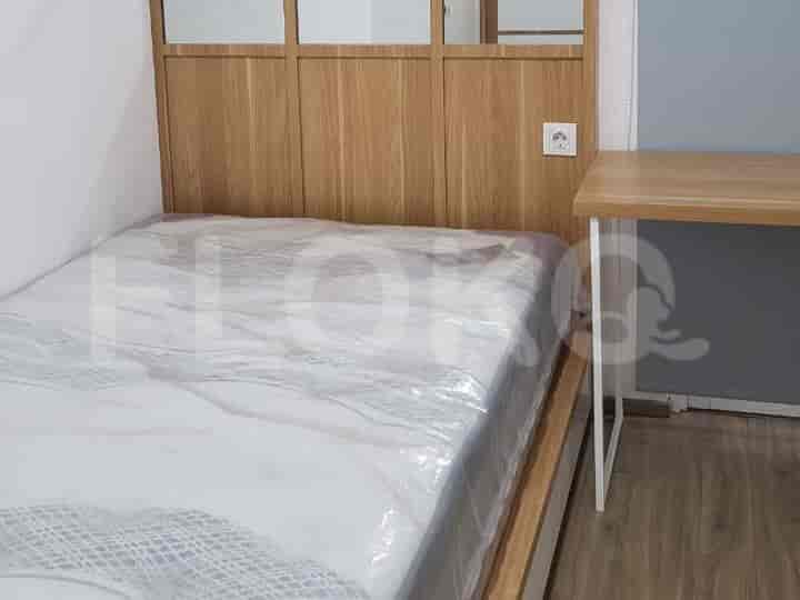 Kamar tidur minimalis dengan tempat tidur yang ditutupi plastik, menampilkan papan kepala kayu.
