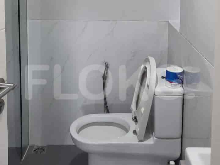 Kamar mandi modern yang menampilkan toilet, semprotan bidet, dan dinding berubin.