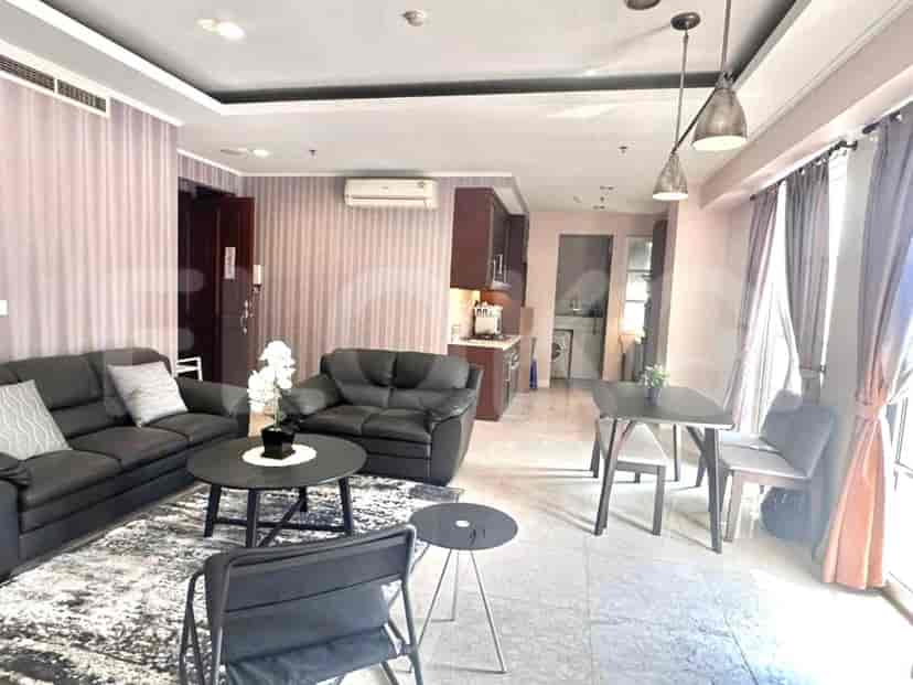 A living room with an L-shaped grey sofa, dining table and open kitchen.
