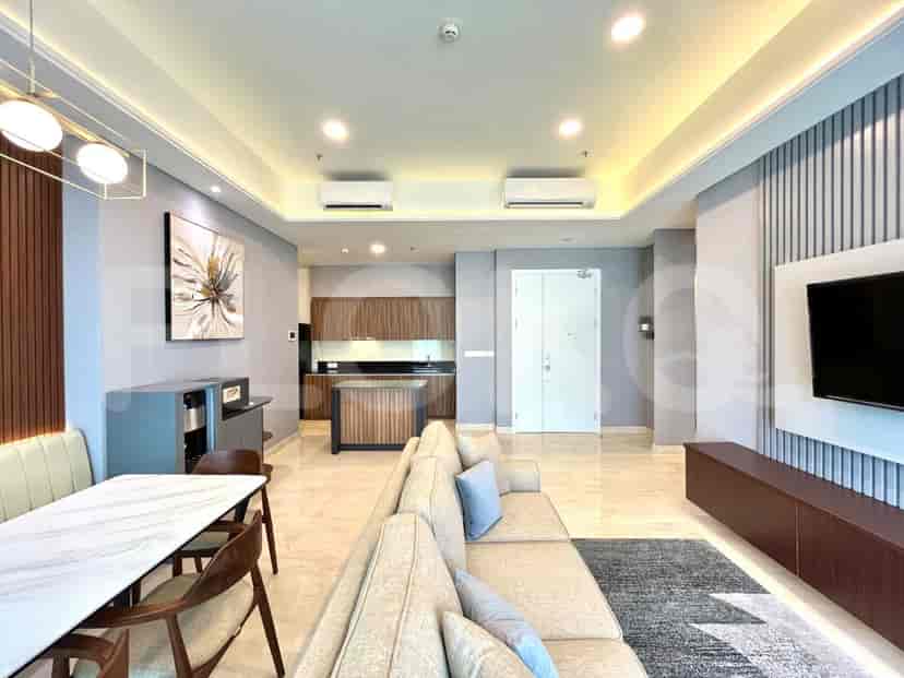 Ruang tamu modern dan kombinasi dapur terbuka dengan sofa berbentuk L abu-abu, lantai marmer, dan lemari kayu.