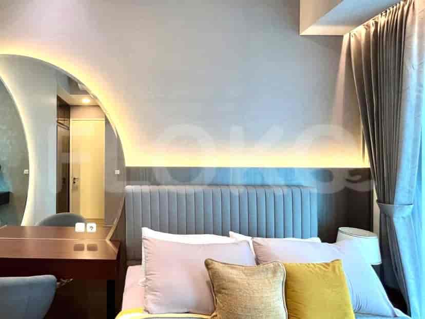 Kamar tidur dengan tempat tidur, headboard built-in, dan meja kerja kecil.