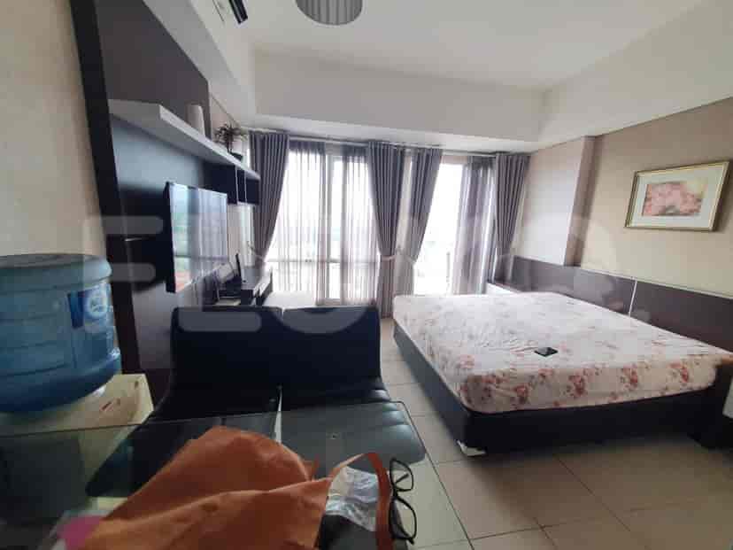 A modern studio apartment with a bed, seating area, and large windows.