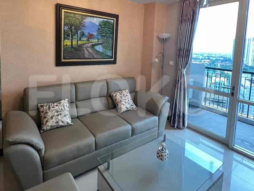 A living room with a grey sofa, painting, and access to a balcony.