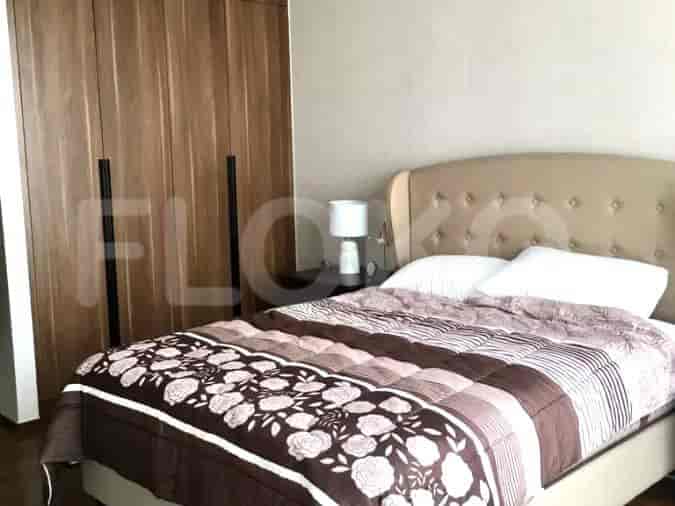 A bedroom with a queen-size bed, wooden closet, and a nightstand.