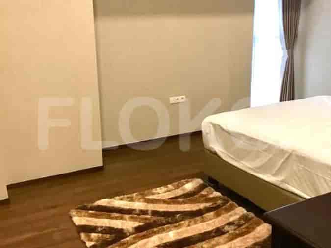 A bedroom with wooden flooring, a bed, and a rug.