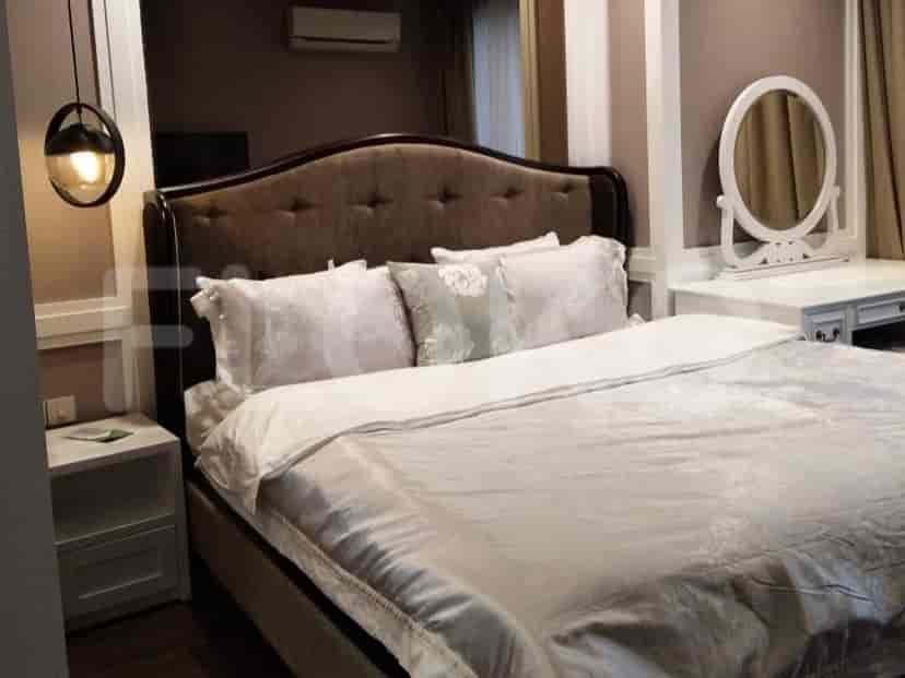 A bedroom with a bed, vanity, and a hanging lamp.