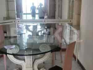 A dining room with a round glass table, chairs, and balcony access.