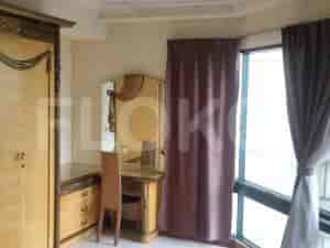 A bedroom with a dresser, dressing table, and window with curtain.