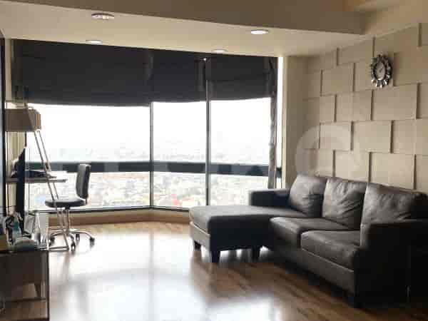 A well-lit living room featuring a large window overlooking the city and a stylish, L-shaped sofa.