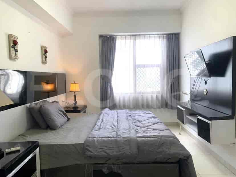 Bedroom with a large bed, TV, and window with curtains.