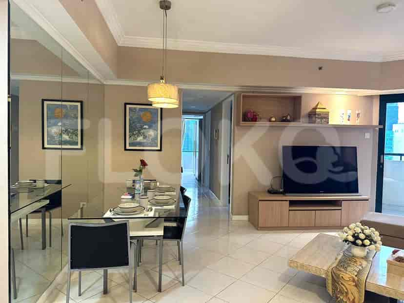 Dining area with a glass table and living room in the background.