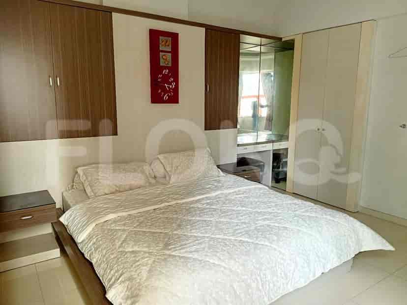 A stylish bedroom with a modern bed, wooden wardrobes, and a wall-mounted clock.