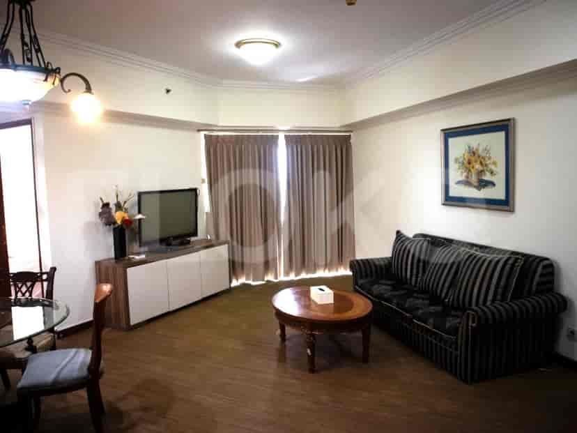 Ruang tamu yang terang dengan TV, sofa, dan area makan yang terlihat.