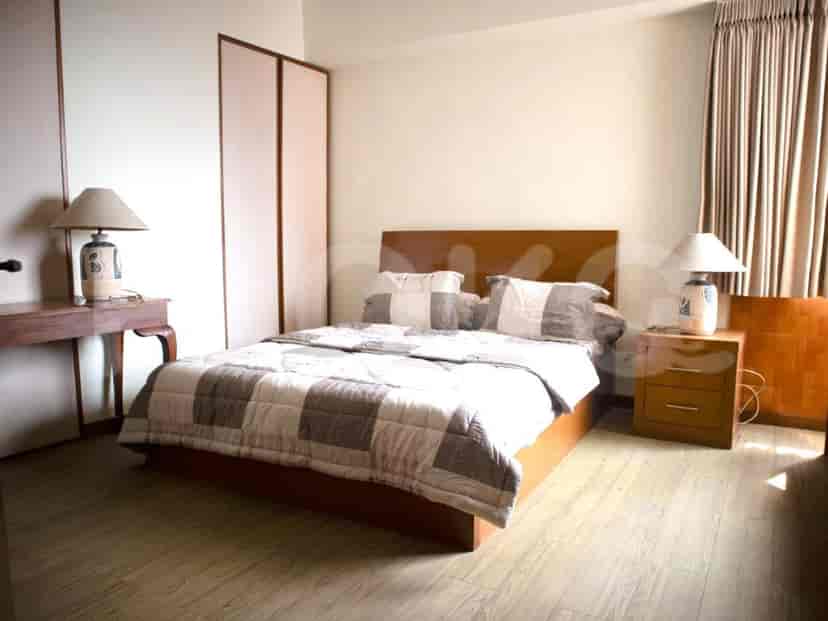 Kamar tidur utama yang luas dengan tempat tidur ukuran king, meja samping, dan lampu.