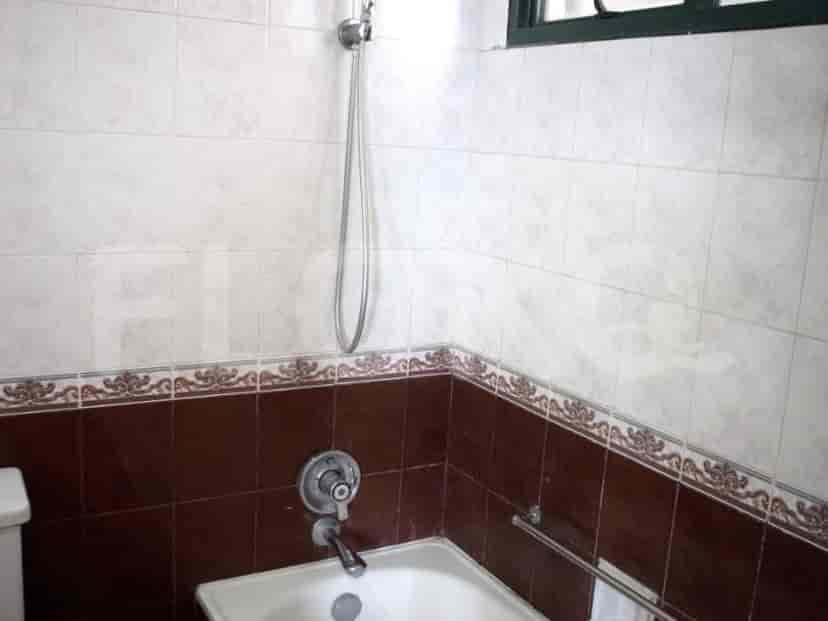Kamar mandi dengan bak mandi, pancuran, dan ubin dekoratif.