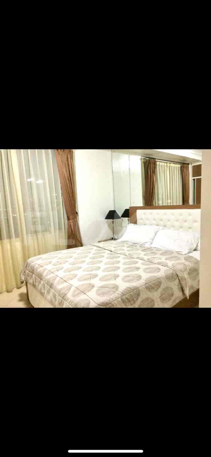A cozy bedroom with a large bed, mirrors, and curtained windows.