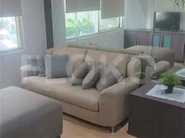 Ruang tamu dengan sofa krem, meja kopi, dan cermin.