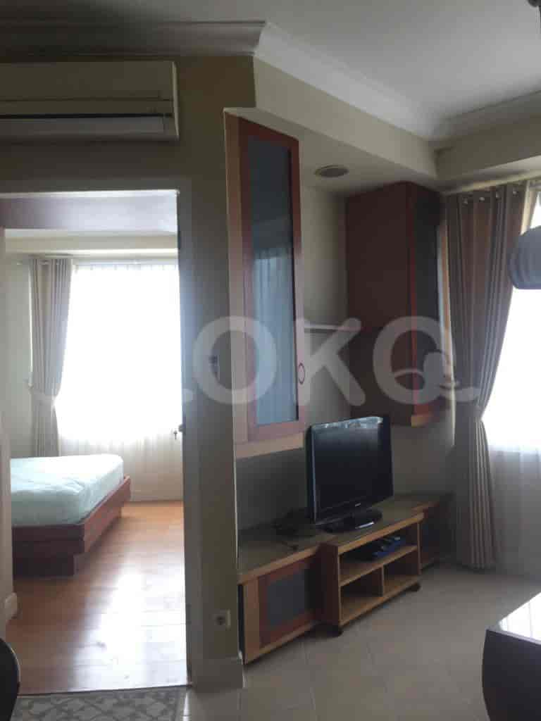 A combined view showcasing the living room with a television and the bedroom beyond.