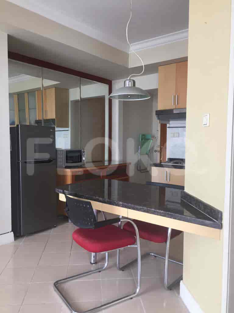 A kitchen showcasing kitchen cabinets, dining table, refrigerator, and a microwave.