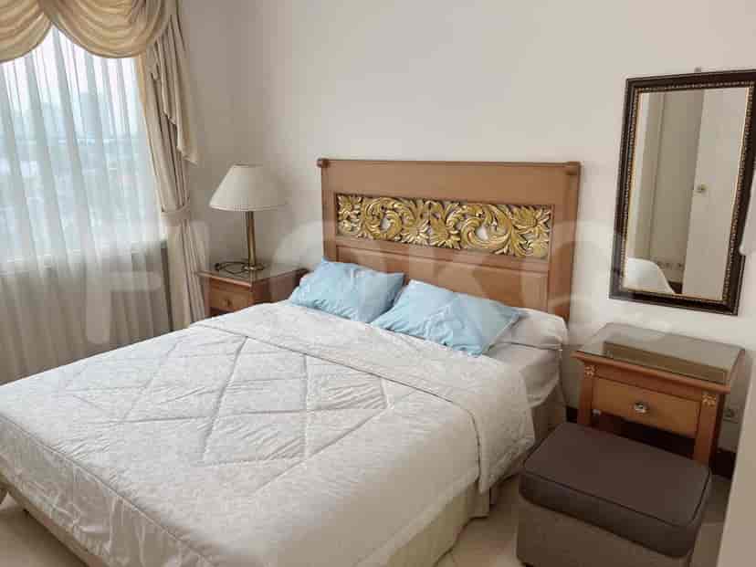 Kamar tidur dengan tempat tidur, meja samping tempat tidur, dan cermin.