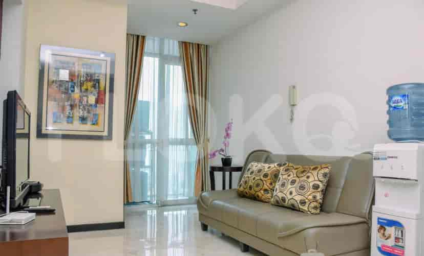 A living room with a grey sofa, artwork, and a large window.