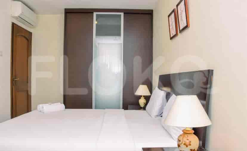 A bedroom with a bed, bedside lamps, and a sliding closet.
